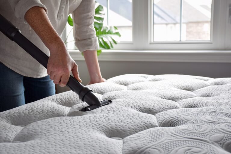 Woman using vacuum cleaner to vacuum mattress in a bedroom