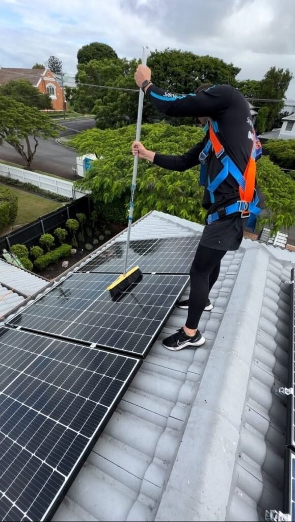 Technician cleaning solar panels with professional equipment on rooftop solar system