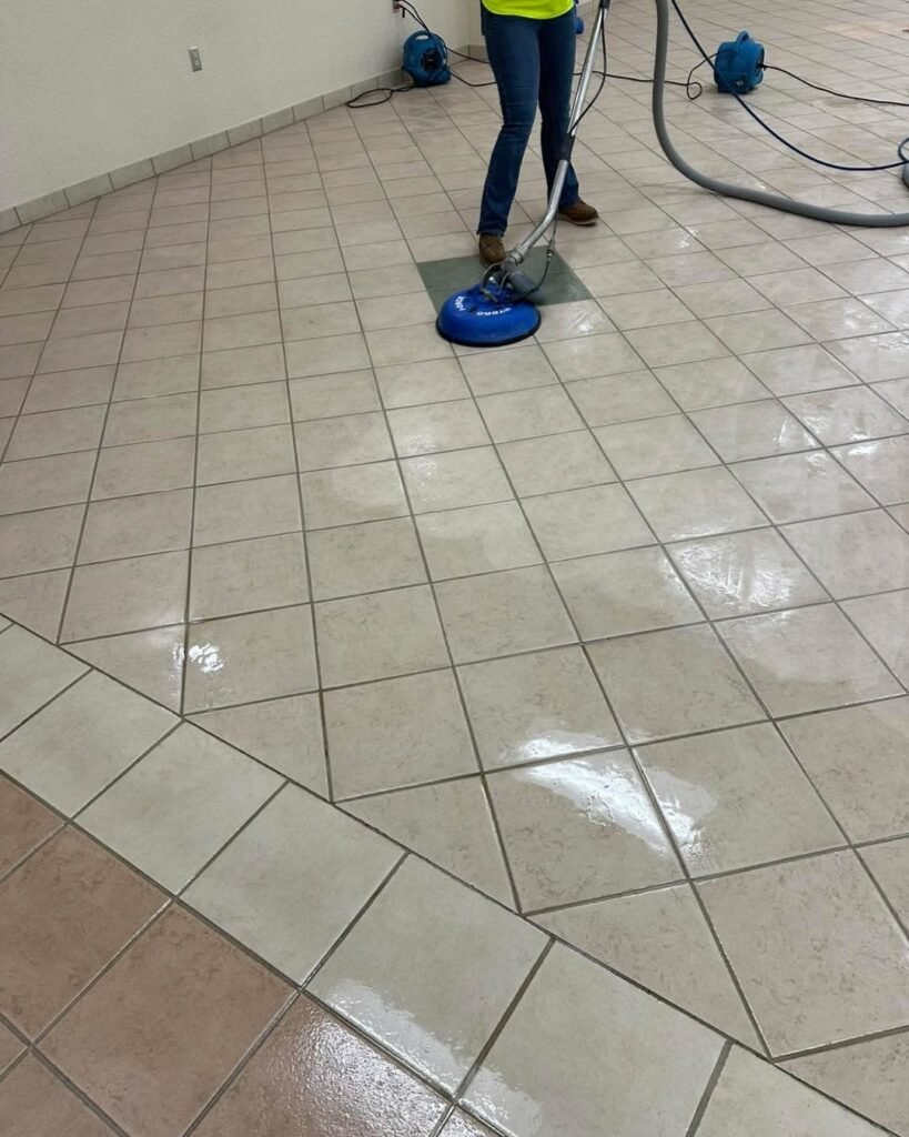 Professional cleaner using a rotary floor cleaning machine to deep clean tiled floor.