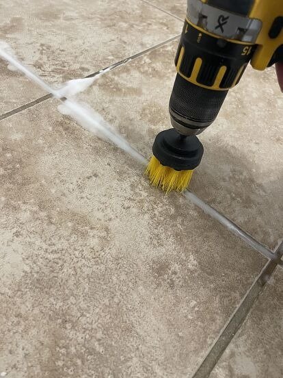 Power drill brush: scrubbing grout lines on tiled floors for deep tile and grout cleaning.