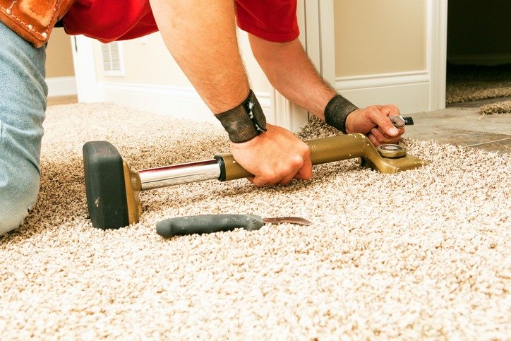 Carpet stretching using knee kicker tool to remove wrinkles and secure carpet