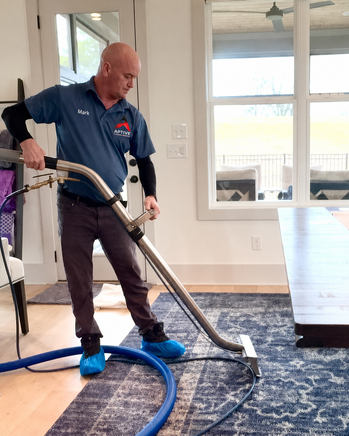 Aptive Cleaning Services technician professionally deep cleaning an area rug using hot water extraction equipment to remove dirt, stains, allergens, and bacteria in a home.