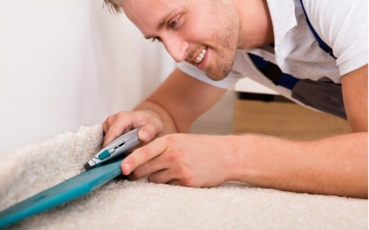 Professional technician trimming and securing carpet edges during Carpet Re Stretching Melbourne using a specialised carpet trimming tool for a precise, seamless finish.