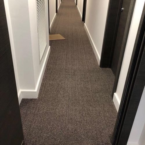 The office corridor features a newly re-stretched commercial hallway carpet with clean and professional carpet finishing.